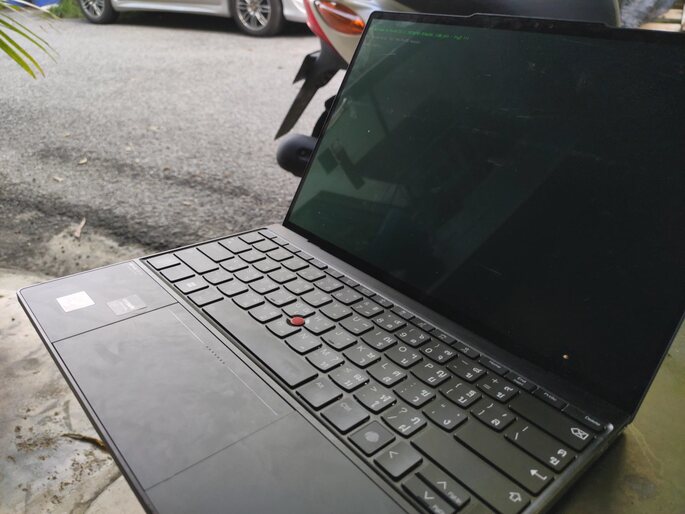 Laptop with display off in an alley with the shadow of the underside of a nearby-car for comparison